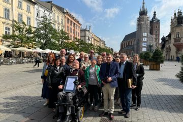 Rynek Główny w Krakowie Janusz Świtaj wśród pracowników i podopiecznych fundacji Mimo Wszystko eksponuje dyplom